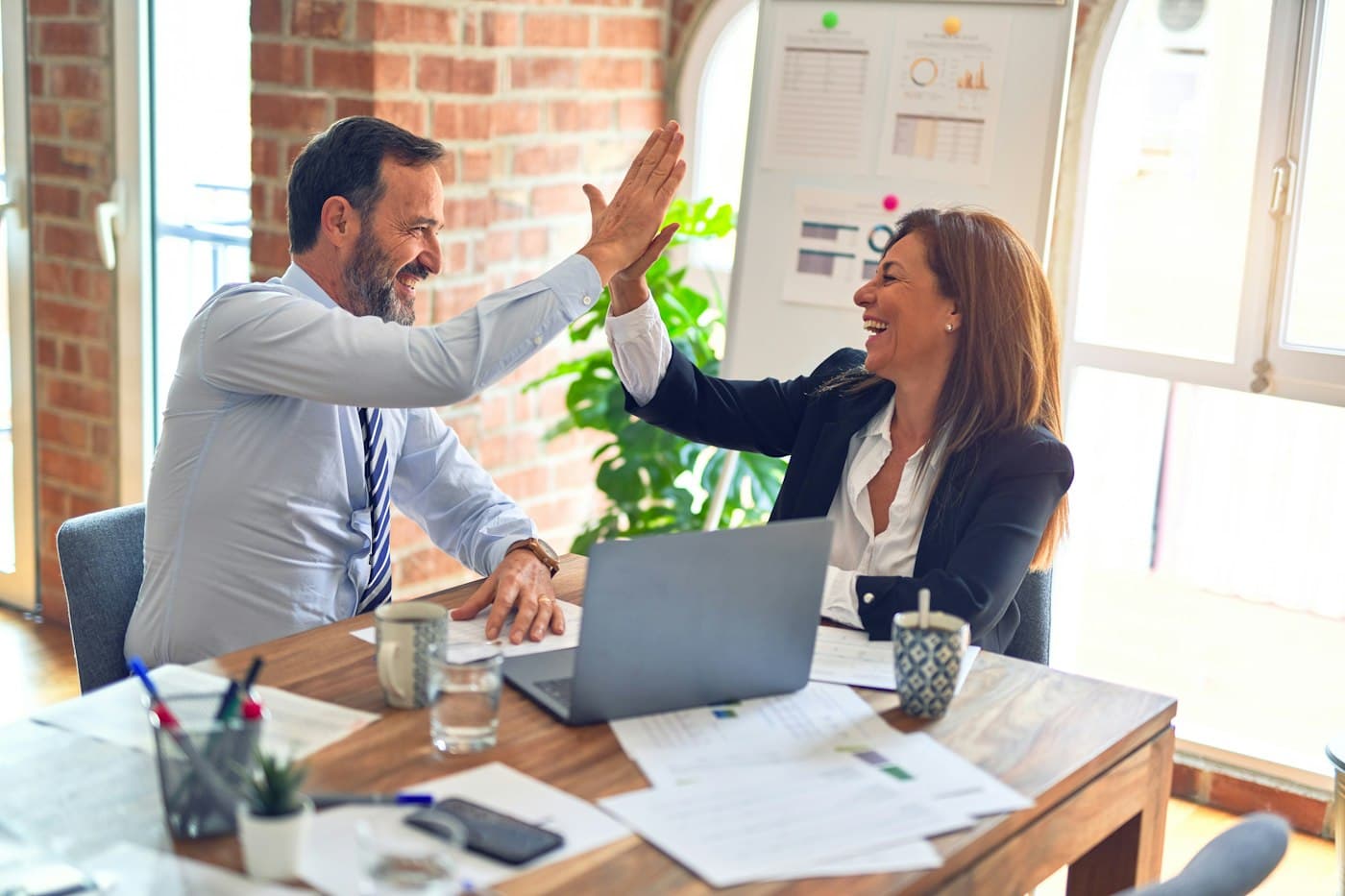 Two colleagues celebrating a new hire in a bright office